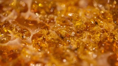 <h3>Pompage des intermédiaires époxy dans la production de résines et de polymères </h3> Close-up macro shot of golden amber-colored epoxy resin crystals with a translucent, glittering texture.