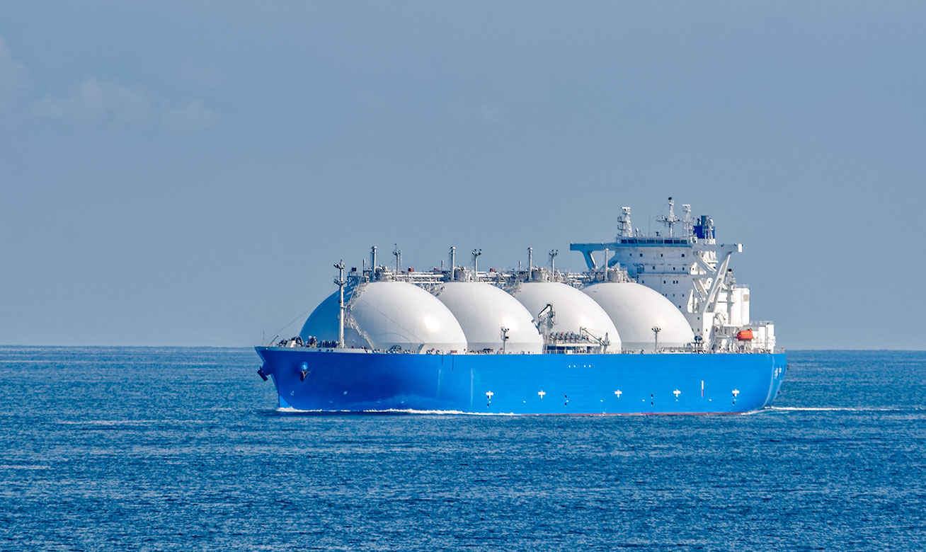 <h2>Pour répondre aux exigences de la mobilité moderne</h2> LNG tanker ship with four large spherical white storage tanks sailing on blue ocean waters