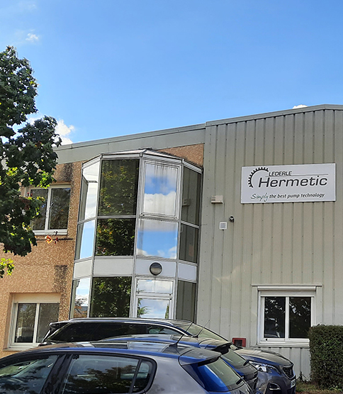 <h3><strong>Développement de l'activité de services en France </strong></h3> Lederle HERMETIC "Simply the best pump technology" company building exterior with glass facade and parked cars.