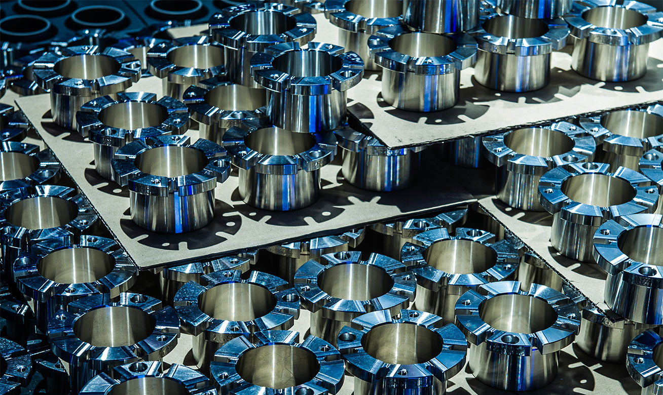 Schnelle Verfügbarkeit von Original-Ersatzteilen von HERMETIC Rows of precision-machined stainless steel cylindrical spare parts components arranged on flat metal sheets in a factory.