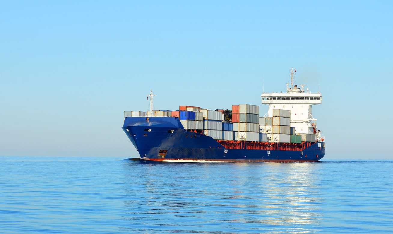 Container ship loaded with colorful cargo containers sailing on calm blue ocean water under clear sky.